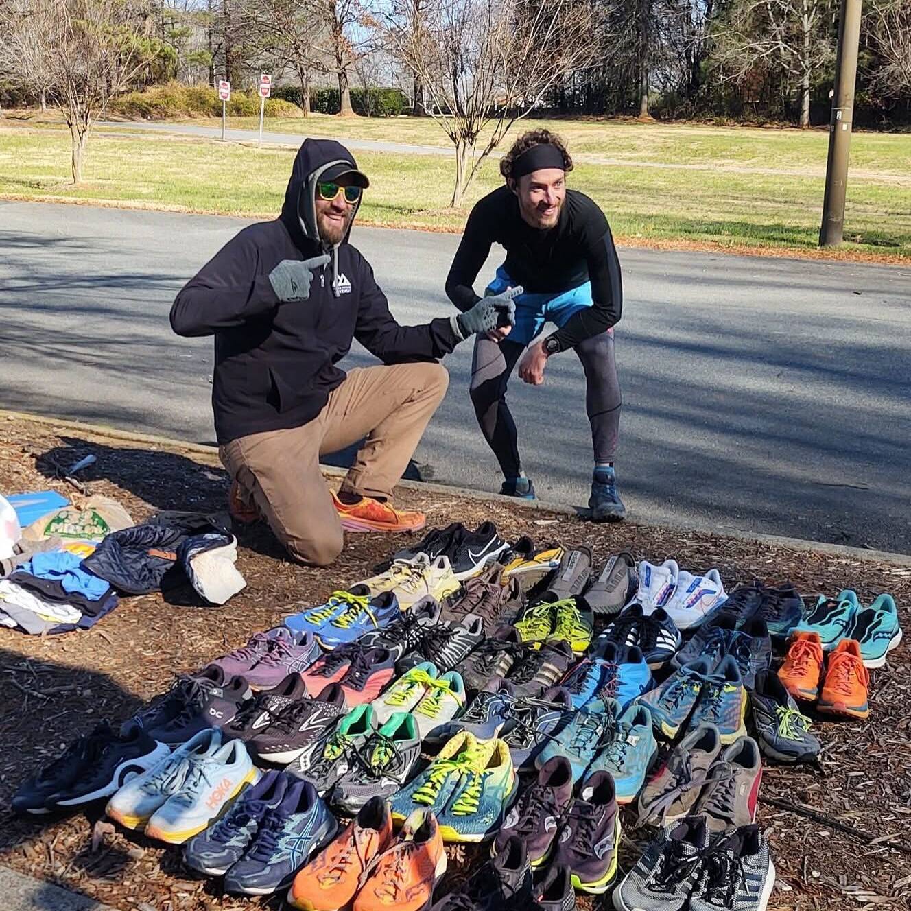 Two runners kneeling beside rows of old running shoes collected for GotSneakers